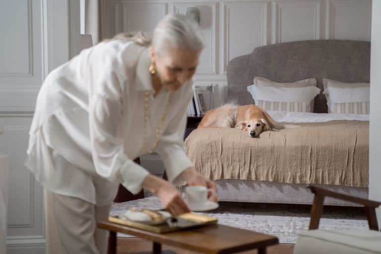 Senior woman with a greyhound lounging in a cozy bedroom setting, enjoying a tranquil morning.